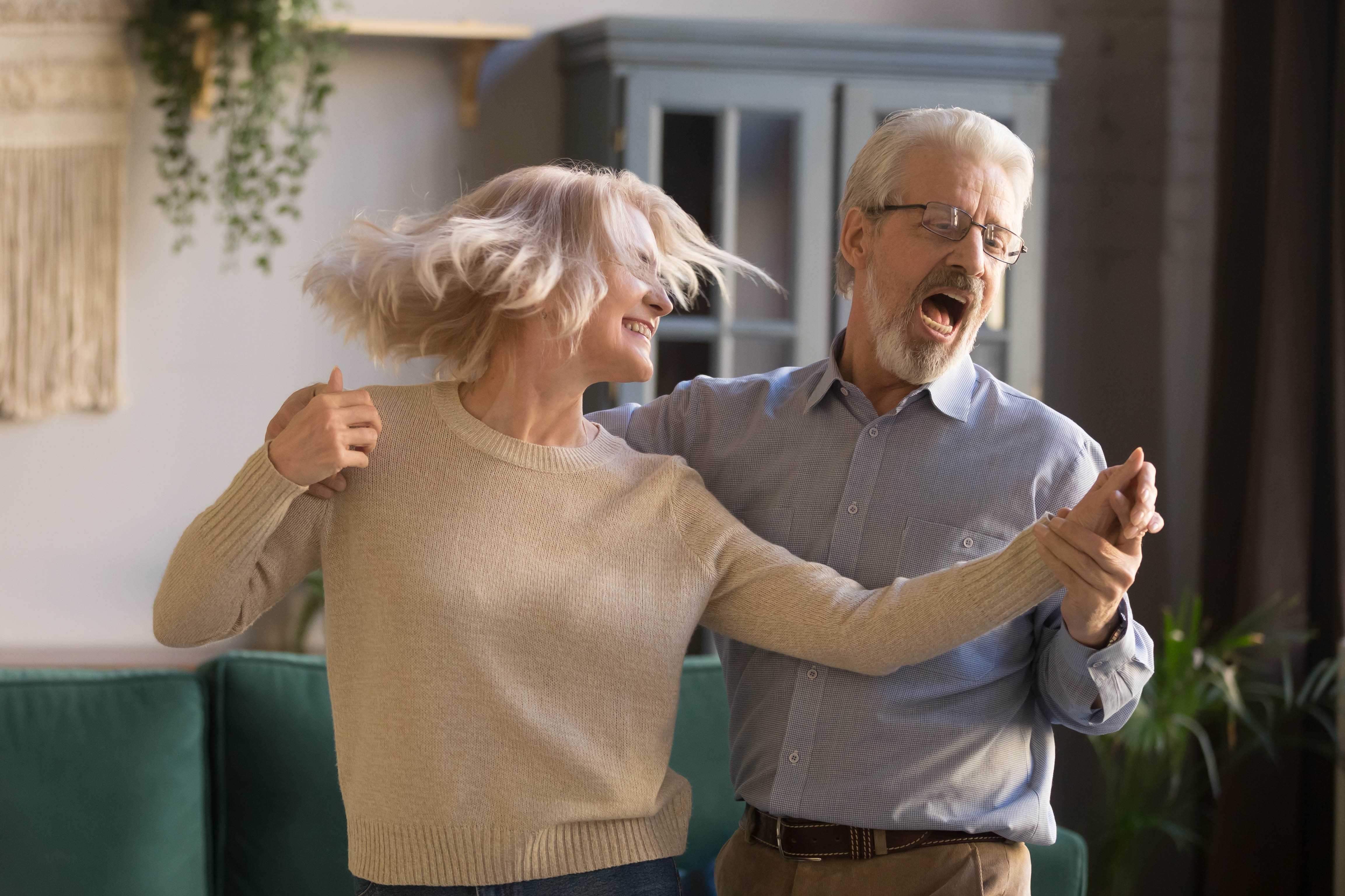 Older couple dancing, laughing, and singing in their living room Older couple dancing, laughing, and singing in their living room